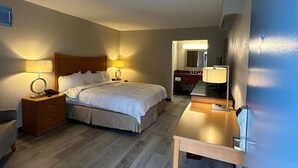 Habitación de hotel con cama, mesitas de noche, escritorio y espejo.