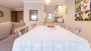 A dining area with a white tablecloth, a chandelier, and a bowl of food. - Oli Coral Canteras (Palmas De Gran Canaria, Las)