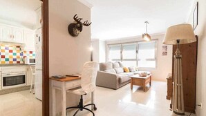 A modern living room with a sofa, a desk, and a lamp. - Oli Coral Canteras (Palmas De Gran Canaria, Las)