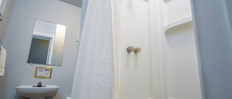 A bathroom with a white sink, a mirror, and a shower curtain.
