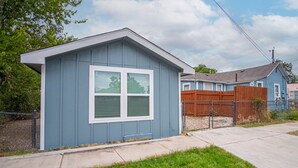 A small, single-story shed with a gabled roof and a large window. - Downtown Accessible New 1BR 1BA Cozy Studio (San Antonio)