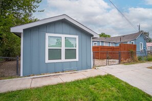 A small, single-story shed with a gabled roof and a large window. - Downtown Accessible New 1BR 1BA Cozy Studio (San Antonio)