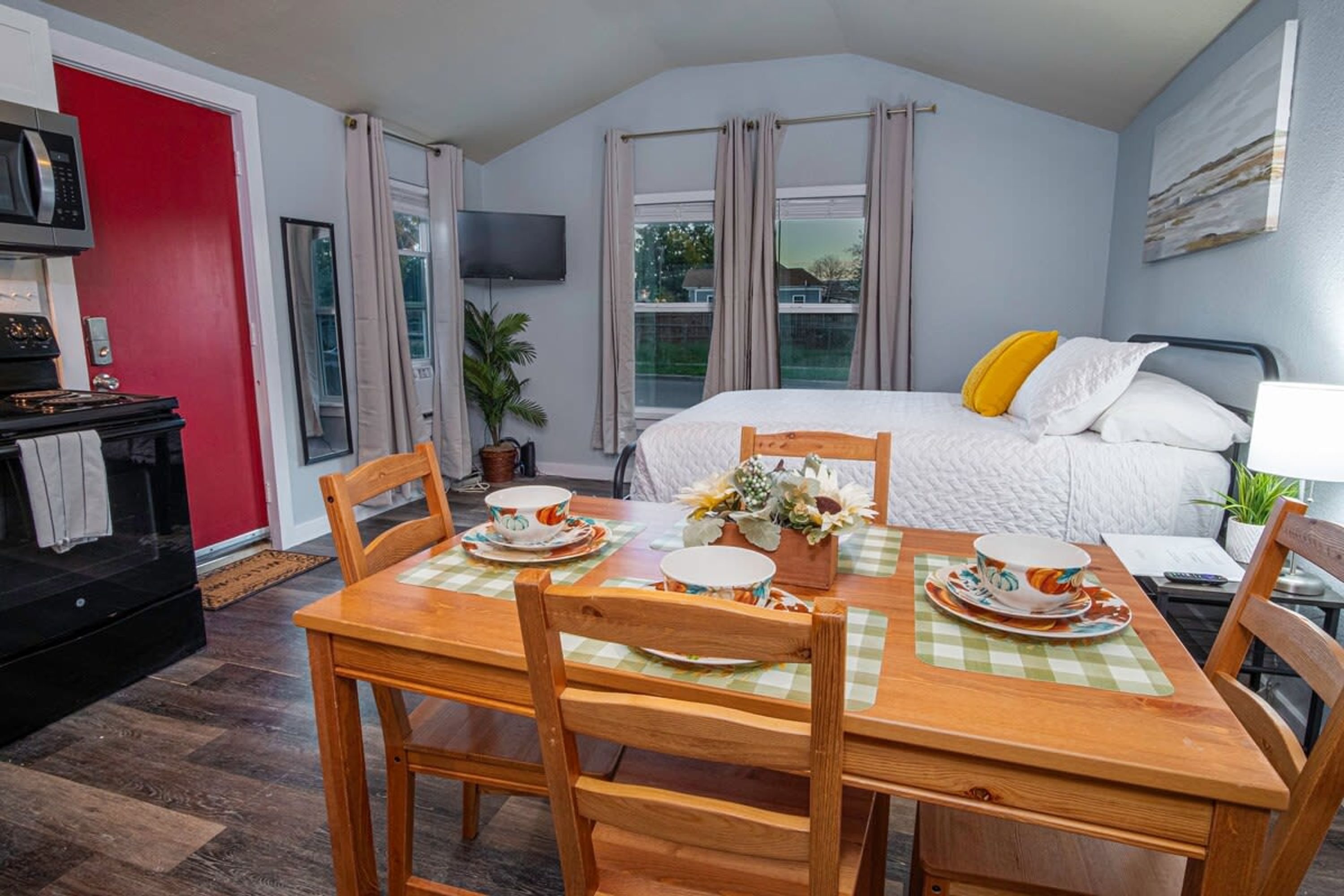 Um quarto aconchegante com cama, televisão e área de refeições com mesa posta para dois.