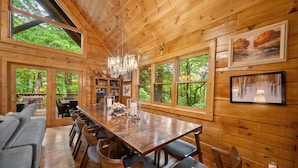 Una cabaña de madera con una gran mesa de comedor, sillas y un sofá.