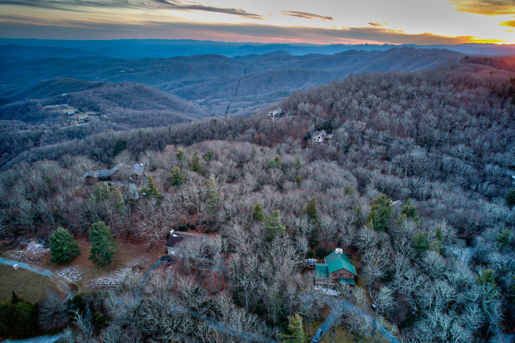 A remote cabin surrounded by dense forest, with a clear view of the surrounding mountainous landscape.