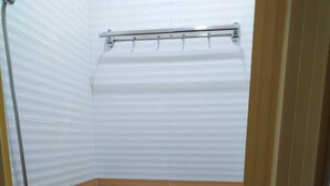 Pieni, käytännöllinen kylpyhuone, jossa on wc, suihku ja wc:n yläpuolella oleva tukikahva.