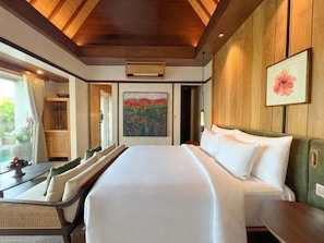 A hotel room with a large bed, a wooden ceiling, a painting, and a view of the outdoors. - The Ridge Bali (Ubud)