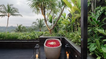 Un jardin sur le toit, avec un grand bac central rempli de fleurs rouges, entouré d’une végétation luxuriante et de palmiers.