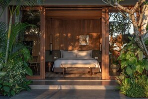 A bedroom with a bed, bedside tables, and a nightstand. - The Ridge Bali (Ubud)
