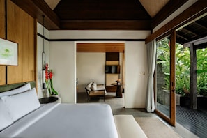 Quarto moderno com uma cama grande, mesa de cabeceira, espelho e vista para um verde exuberante através de uma porta de vidro deslizante.