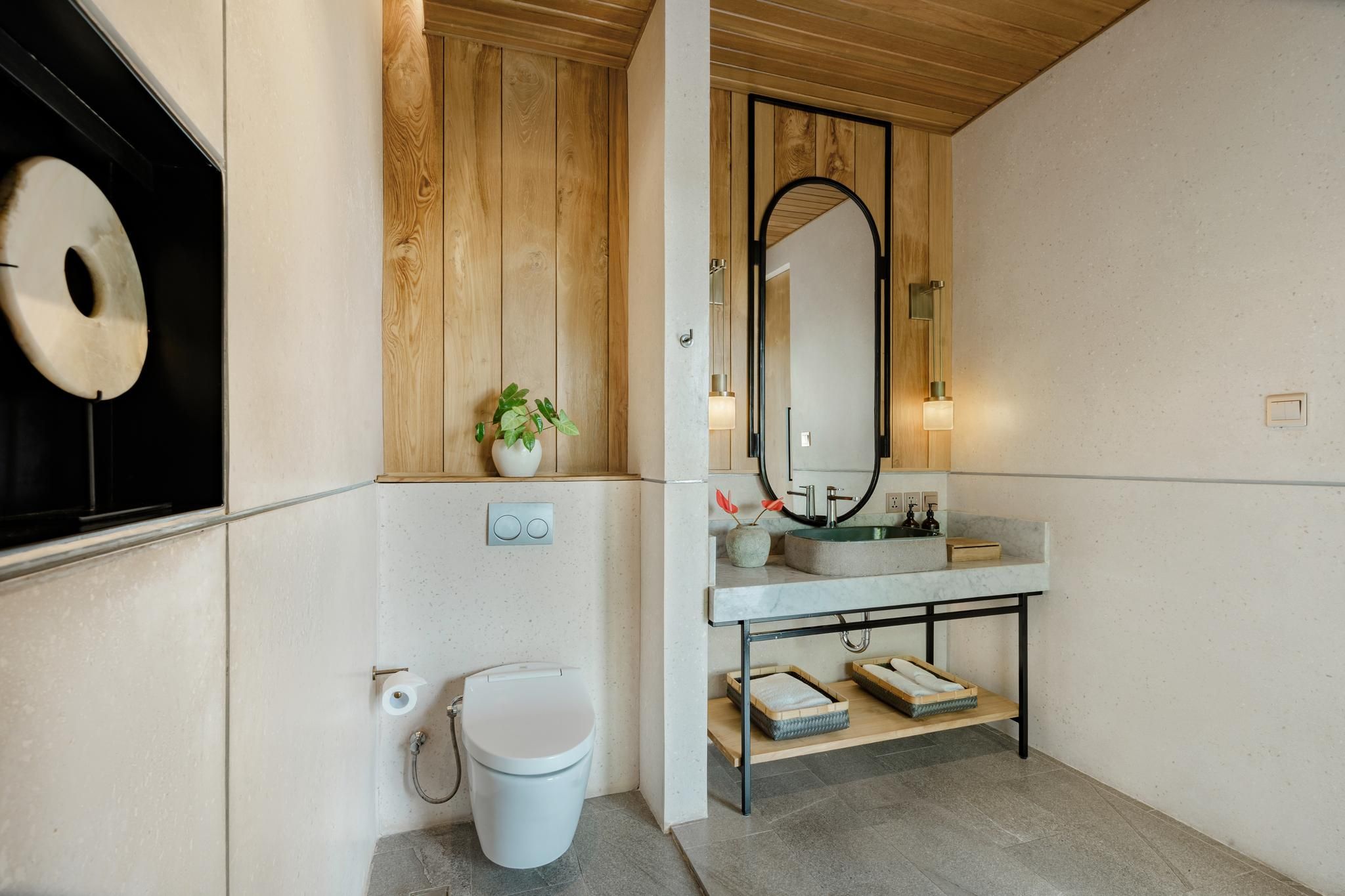 Un baño moderno con inodoro, lavamanos y espejo.
