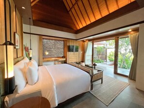 A hotel room with a large bed, a flat-screen TV, a dining table, and a sliding glass door leading to an outdoor area.