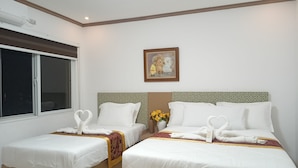 A hotel room with two beds, each with neatly arranged towels and a decorative vase with flowers.