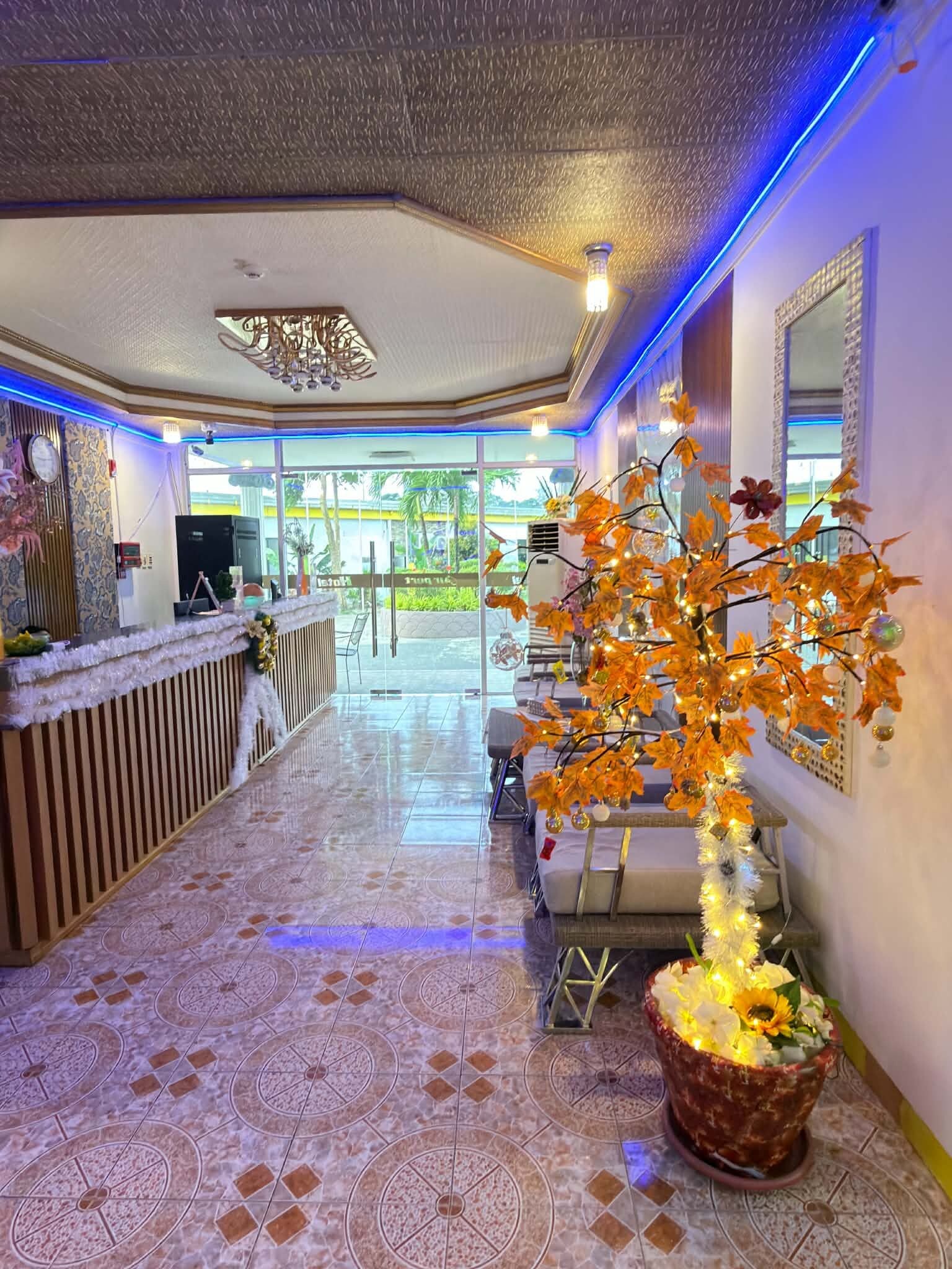 A hotel lobby with a reception desk, a decorative tree, and a view of the outdoors.