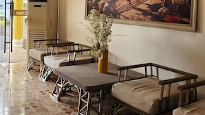A lobby with a large painting, wicker furniture, and a tiled floor.
