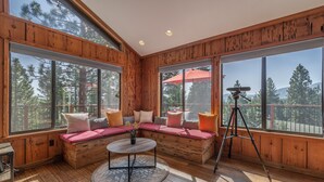 Ein gemütliches Blockhaus-Interieur mit großen Fenstern, einer Holzterrasse und einem Stativ.