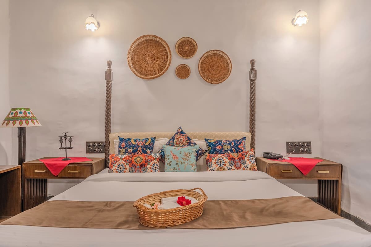 Un dormitorio ordenado con una cama grande, dos mesitas de noche, una lámpara y adornos en la pared.