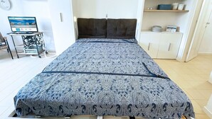 Une chambre à coucher comprenant un lit, un bureau, une chaise, une étagère avec des livres et une armoire.