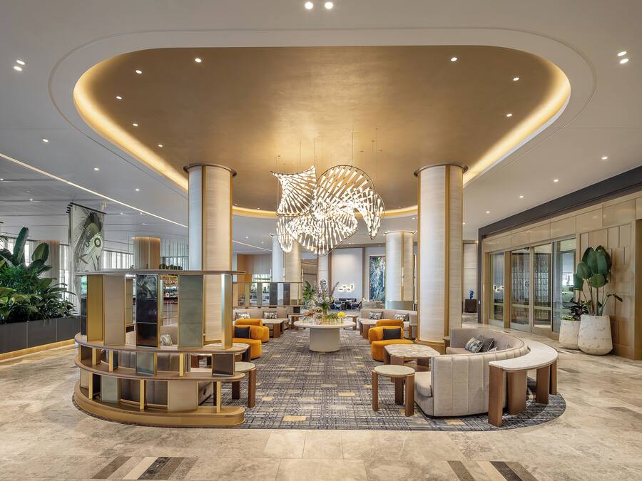Un hall d’entrée spacieux avec un espace salon central, de grandes colonnes et une sculpture au plafond remarquable.