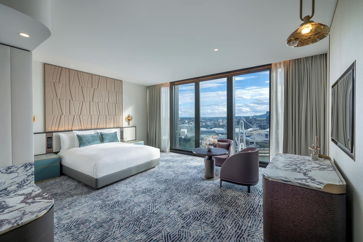 Ein modernes Hotelzimmer mit einem großen Bett, einer Sitzecke und Blick auf die Stadt.