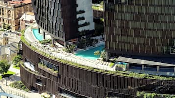 A modern building with a rooftop pool, surrounded by greenery and a curved design.