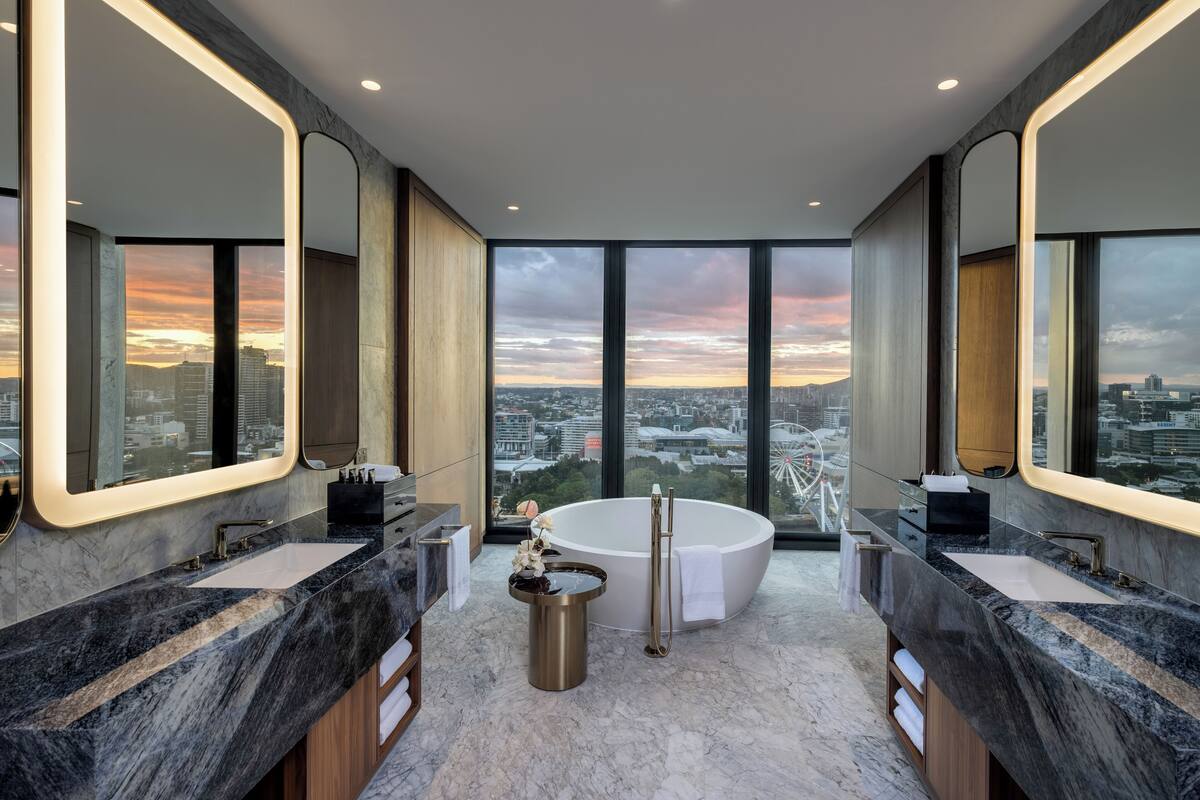 Ein modernes Badezimmer mit zwei Waschbecken, einer freistehenden Badewanne und großen Spiegeln.