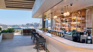 Un espace bar moderne avec vue sur la ville, des tabourets de bar et un appareil à café.