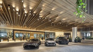 Eine moderne Hotelhalle mit einer Rezeption, drei Luxusautos und einem außergewöhnlichen Deckenstil.