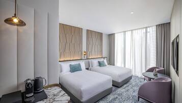 Habitación de hotel con dos camas, un escritorio, una silla, una cafetera y un televisor.