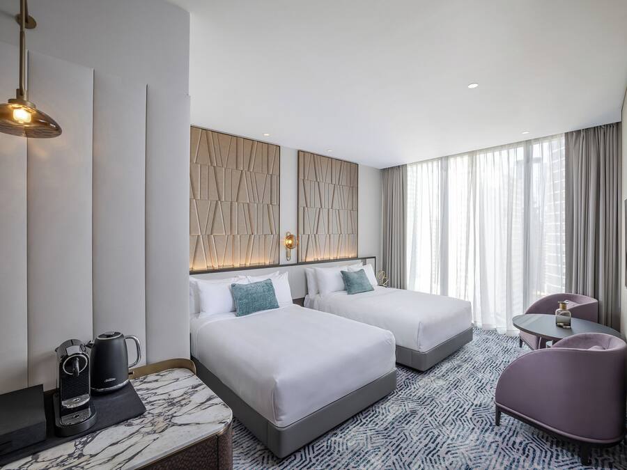 Habitación de hotel con dos camas, un escritorio, una silla, una cafetera y un televisor.