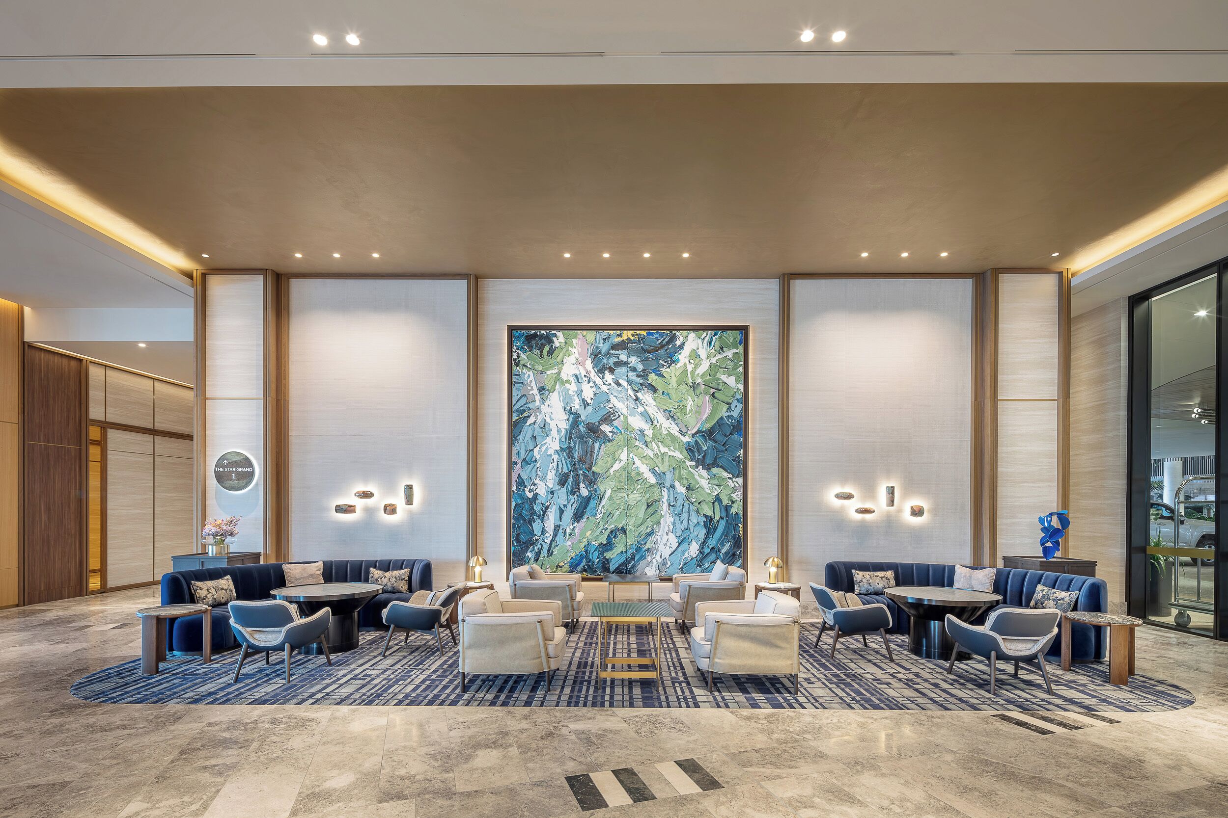 A modern lobby with a large abstract painting, seating area, and a reception desk.