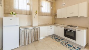 Een moderne keuken met witte kasten, een inbouwoven en een gasfornuis.