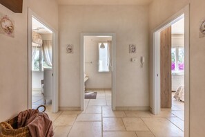 A hallway leading to a bathroom with a tiled floor and a door on the right.