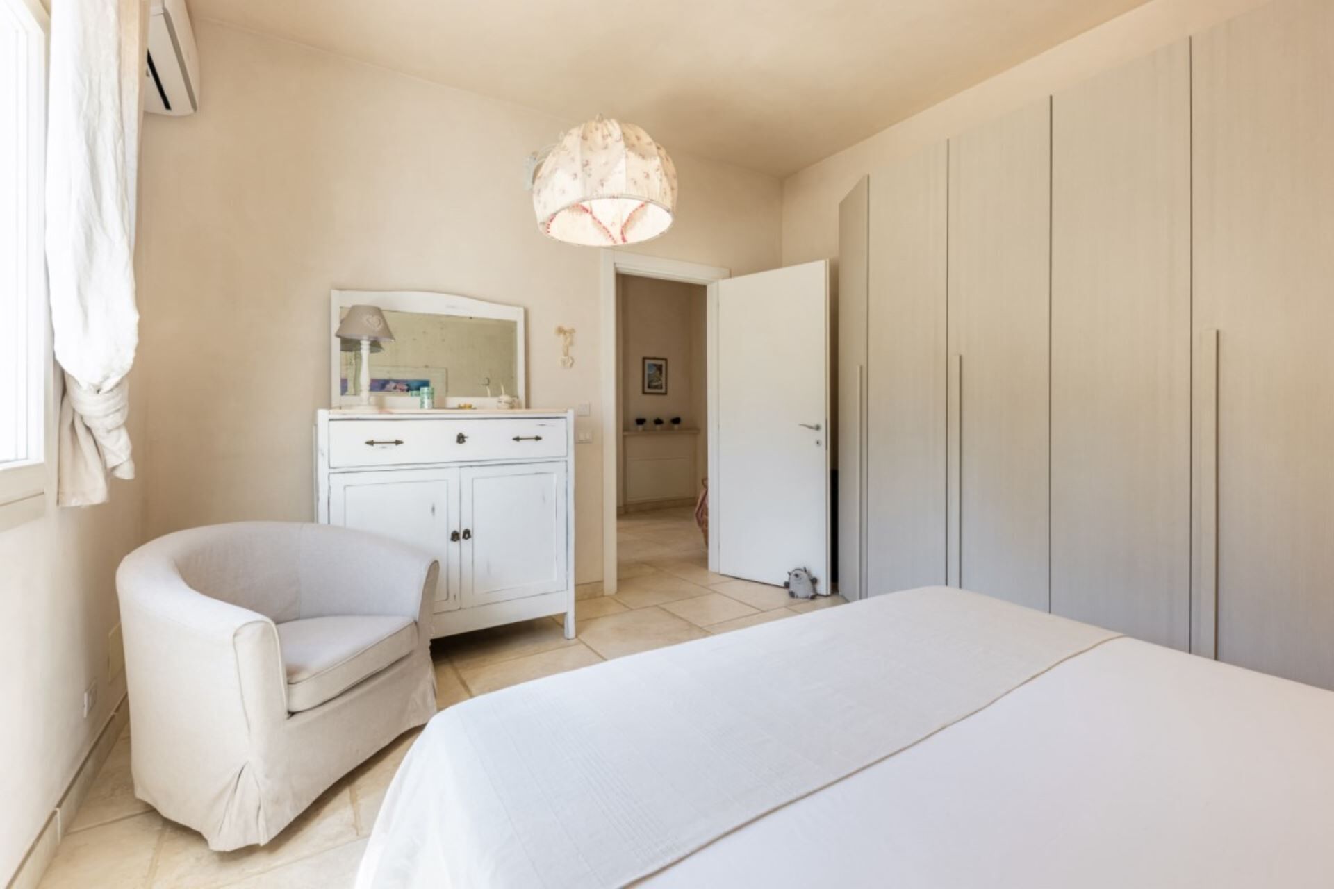 Ein Schlafzimmer mit Bett, Stuhl, Schrank und Spiegel.