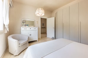A bedroom with a bed, a chair, a wardrobe, and a mirror.