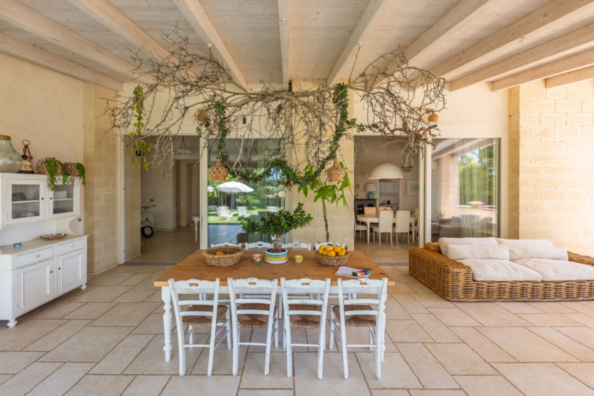 Un coin repas avec une table en bois, des chaises blanches et une plante suspendue.