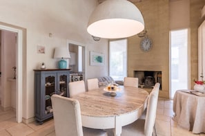 A dining area with a round table, chairs, a lamp, a cabinet, and a fireplace.