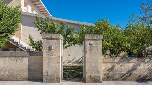 A stone gate with a number plaque, a staircase, and a building with a clear blue sky in the background. - Exclusive Villa Reginella with pool in Lecce (Lecce)