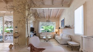 A spacious living area with a sofa, a television, and a dining area with chairs and a table. - Exclusive Villa Reginella with pool in Lecce (Lecce)