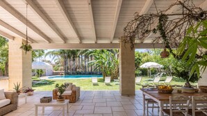 Un patio esterno con piscina, sedie a sdraio e zona pranzo.
