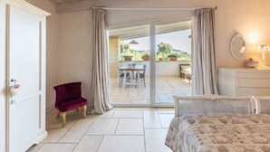 A bedroom with a bed, a chair, a dresser, and a view of an outdoor patio with a table and chairs. - Exclusive Villa Reginella with pool in Lecce (Lecce)