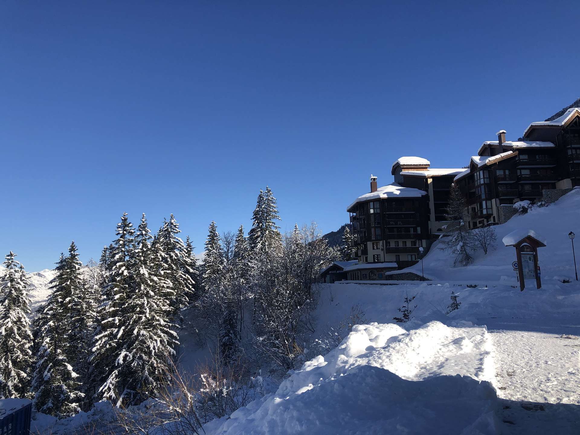 A snow-covered mountain lodge with multiple balconies and a clear blue sky.