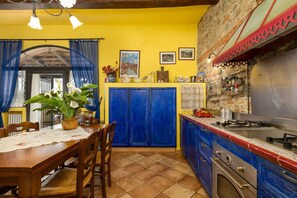 A kitchen with blue cabinets, a dining table with chairs, and a stove.