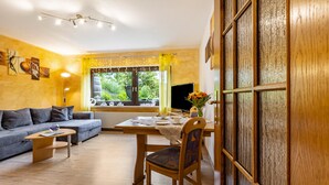 Ein gemütliches Wohnzimmer mit einer Couch, einem Esstisch und einem Fernseher.