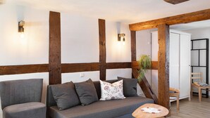 Ein modernes Wohnzimmer mit grauem Sofa, Holzbalken und einem kleinen Tisch.