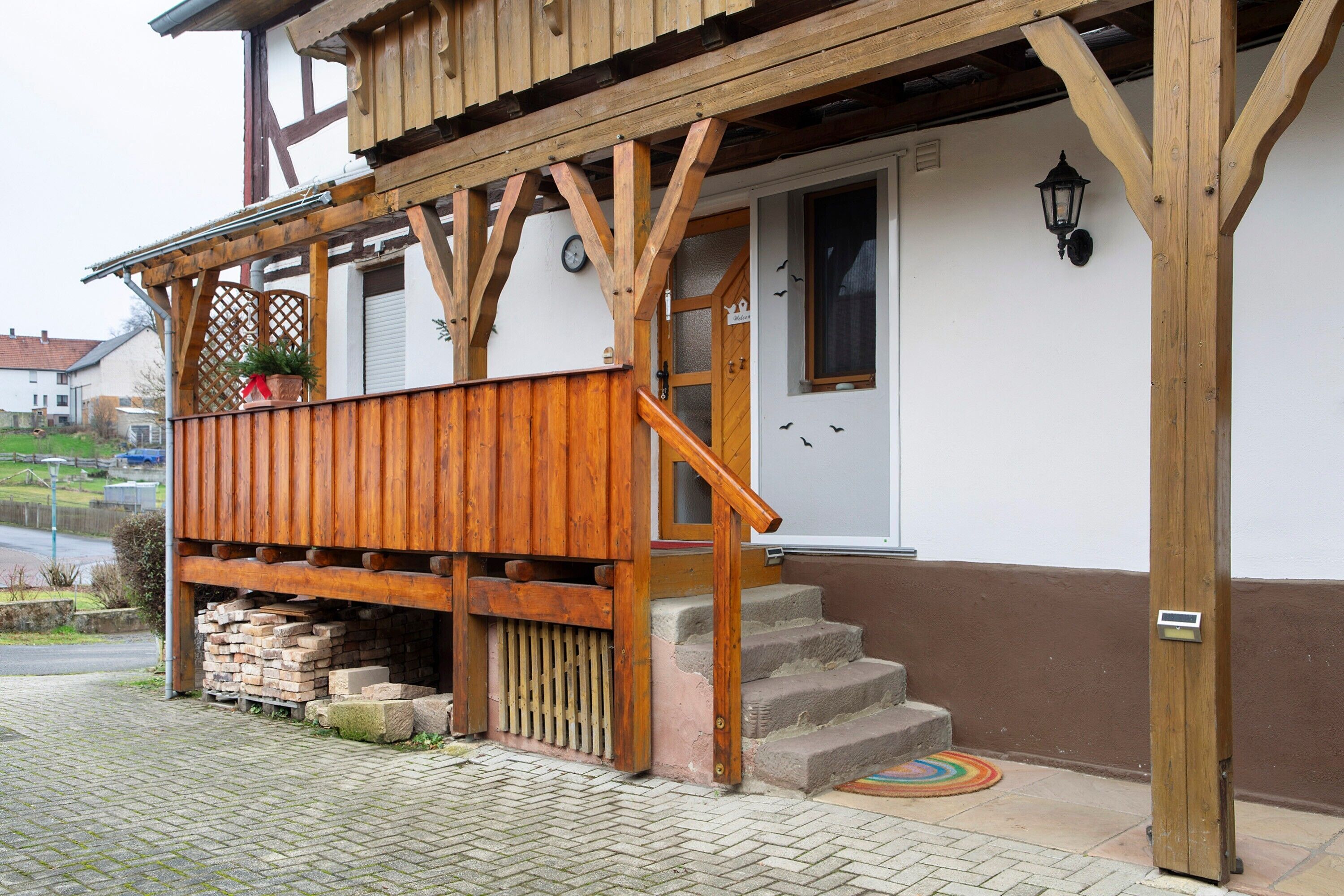 Un bâtiment en bois doté d’un porche, d’un escalier et d’une porte.