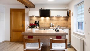 Eine Küche mit Holzausstattung, einer zentralen Kochinsel, zwei Stühlen, einer Kaffeemaschine und einem Blumentopf.