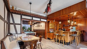 A cozy room with a pool table, wooden bar, and bar stools.