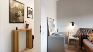 Un salon moderne avec un canapé, une petite table surmontée d’une lampe et des tableaux encadrés accrochés au mur.