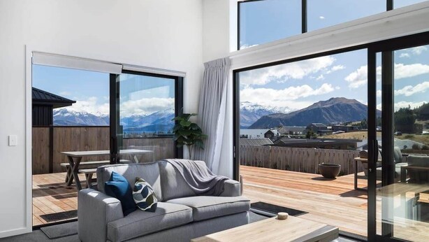 Un salon moderne avec un canapé, une table basse et de grandes fenêtres donnant sur une vue imprenable sur les montagnes.